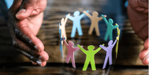Dark skin tone hands cup a ring of paper people in various colours.