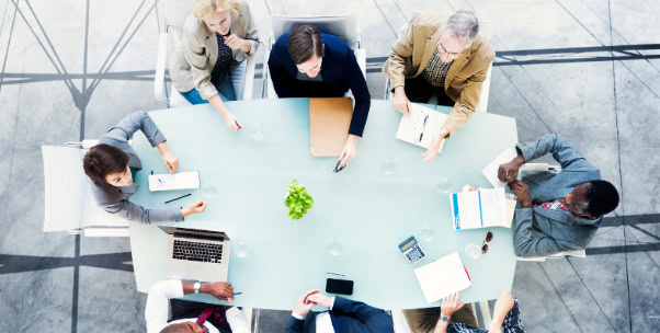 Diverse people around a table sharing ideas for leadership and execution.